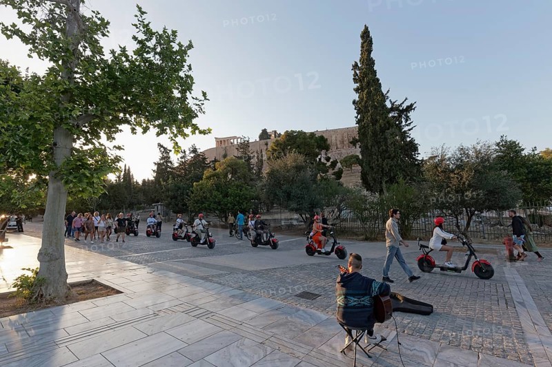 Row of tourists riding on e-chopper on Dionysiou Areopagitou, pedestrian street with view of the Acropolis, evening light, Athens, Greece, Europe