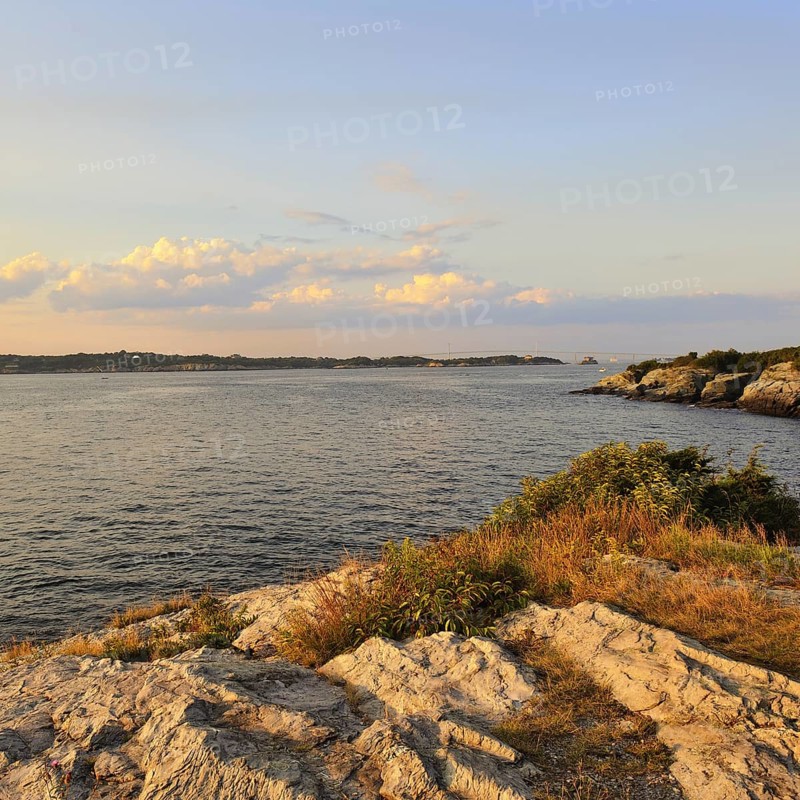 Seascape of Narragansett Bay at twilight from rocky cliffs of Castle Hill, Newport, Rhode Island, United States, North America. Distant view of Claiborne Pell Newport Bridge seen near horizon, North America