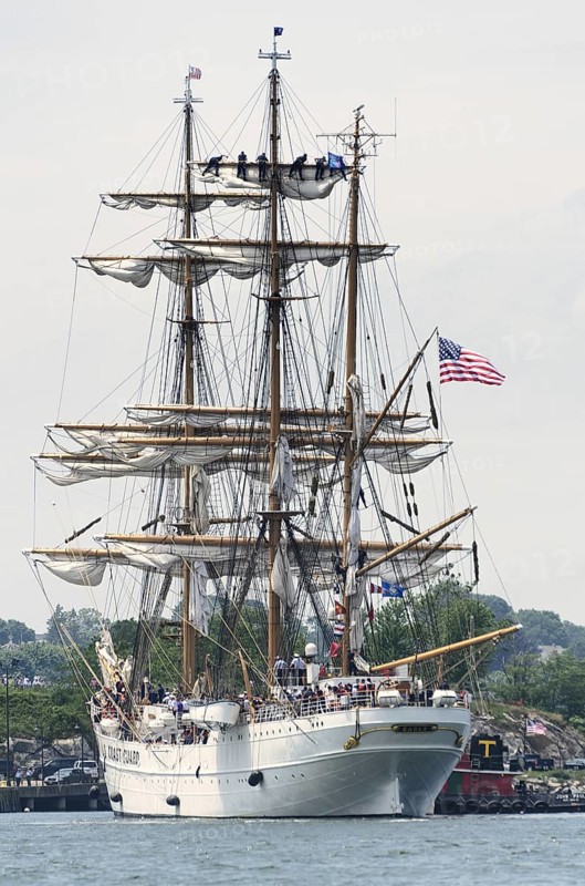 New London, Connecticut, USA, July 2012: Crew members high up in the rigging furl the sails on the US Coast Guard cutter Eagle when it arrives at Fort Trumbull, New London, Connecticut at the conclusion of the Parade of Sail during Operation Sail 2012. OpSail 2012 celebrated the bicentennial of the War of 1812 and the penning of the Star Spangled Banner, the US National Anthem. New London is the Eagle's homeport. Originally a German vessel, the ship was built in 1936 by the Blohm and Voss Shipyard in Hamburg, Germany. The square rigger is a training vessel for US Coast Guard cadets. While underway, the Eagle's crew must handle more than 22, 000 square feet of sail and five miles of rigging, North America