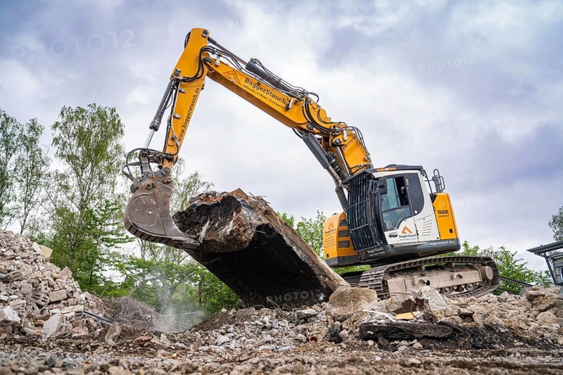 An excavator picks up large pieces of concrete on a construction site, surrounded by rubble and trees, demolition site, Saarbrücken, Germany, Europe
