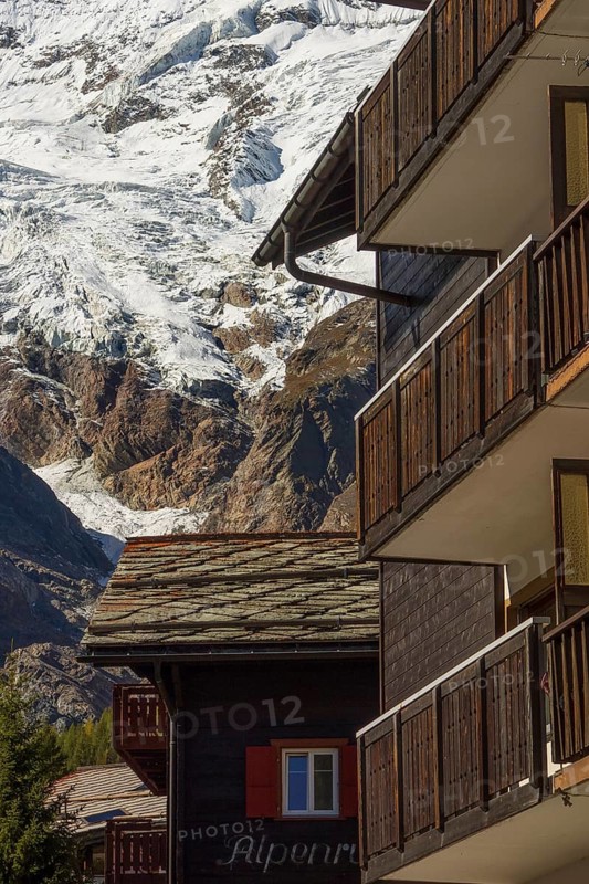 Wooden balconies in a mountain village, with snow-capped mountains in the background, Saas Fee, Switzerland, Europe
