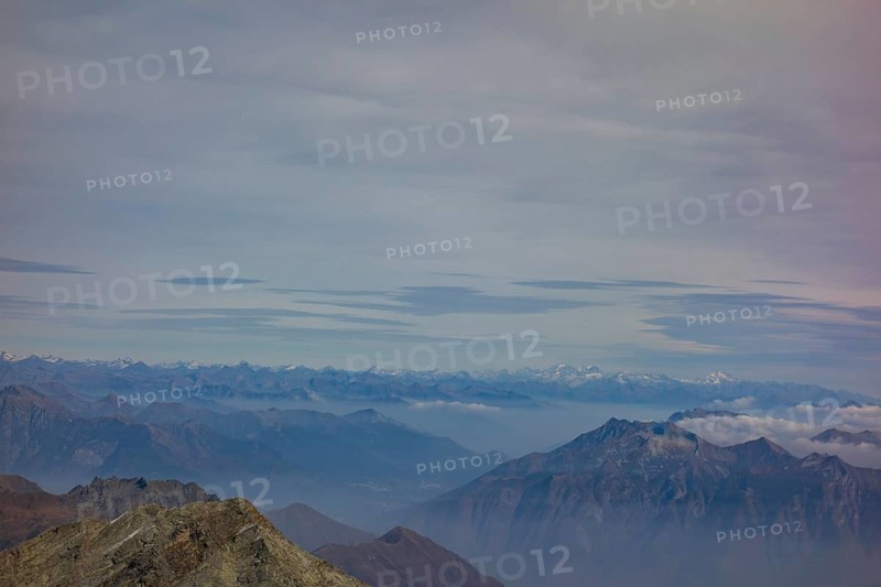 A vast mountain landscape with visible peaks and distant mountain ranges under a cloudy sky, Saas Fee, Switzerland, Europe
