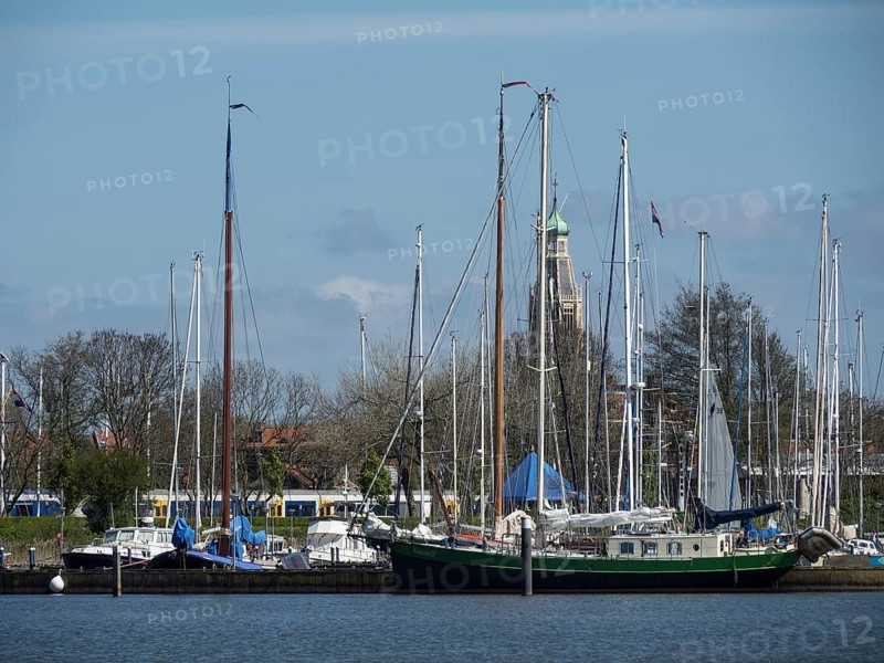 View of a harbour with sailing boats and a historic bell tower in the background, calm water, enkhuizen, the netherlands