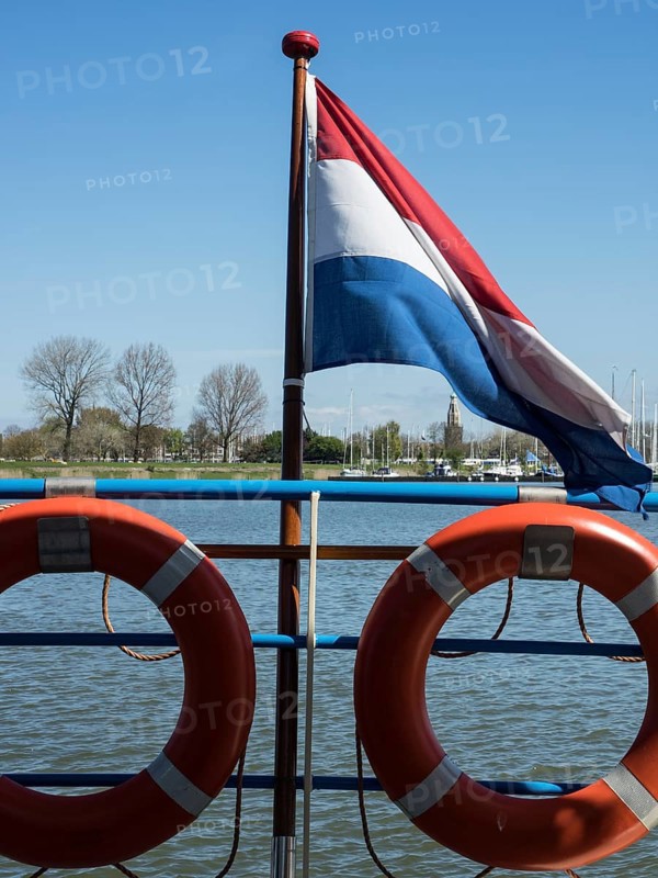 Dutch flag and lifebuoys on a jetty under a clear sky, enkhuizen, the netherlands