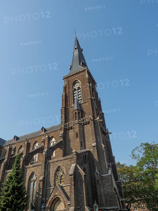 Large Gothic church with high tower and pointed arch windows made of red brick under a clear sky, Maastricht, Limburg, Netherlands