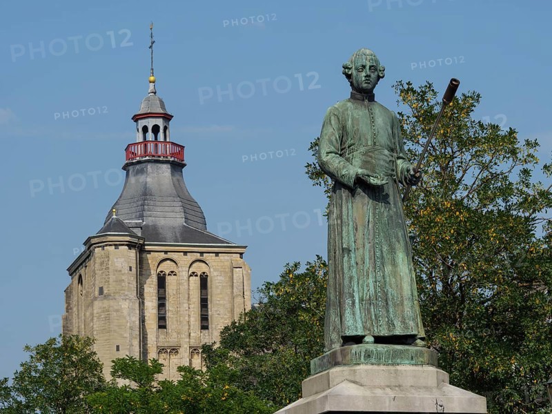 Bronze statue in front of a church building and green trees under a blue sky, historical monument, Maastricht, Limburg, Netherlands