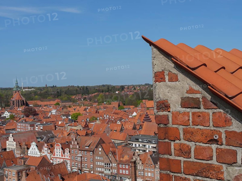 View over the red roofs of a city, calm and clear view with church tower in the background, view over an old town with red roofs around imposing church towers, Lüneburg, Germany, Europe