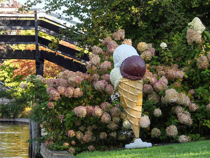 Large ice-cream cone decoration between hydrangea flowers on a canal next to a wooden bridge, giethoorn, Netherlands