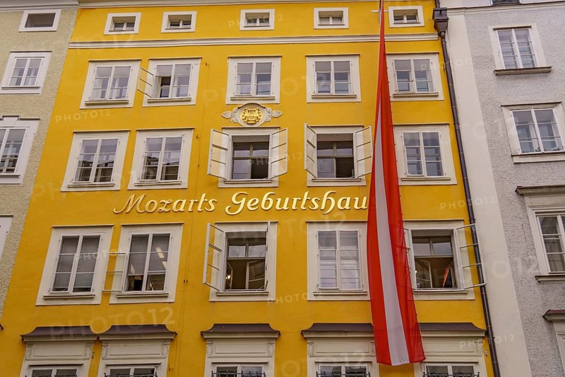 Yellow historical building with the inscription Mozart's birthplace and an Austrian flag, Salzburg, Austria, Europe