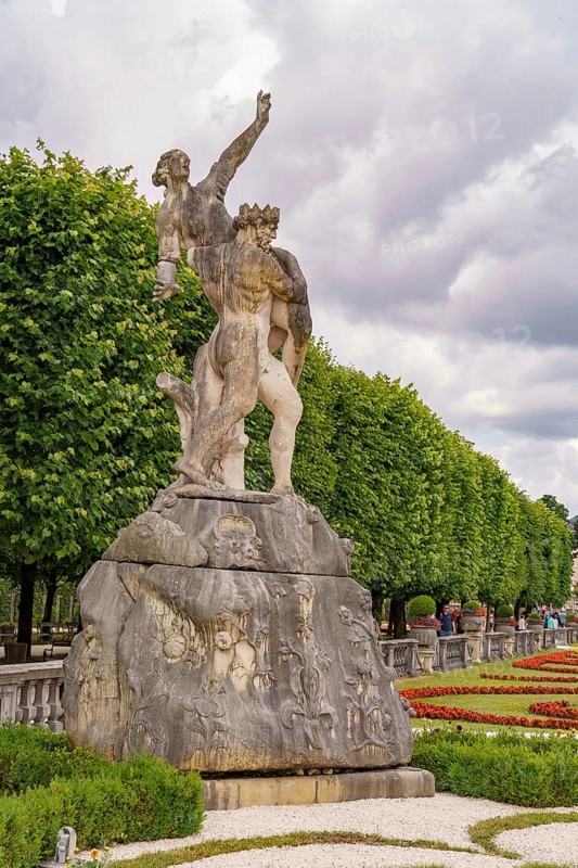 An imposing stone statue in front of an avenue of trees in a historic park, Salzburg, Austria, Europe