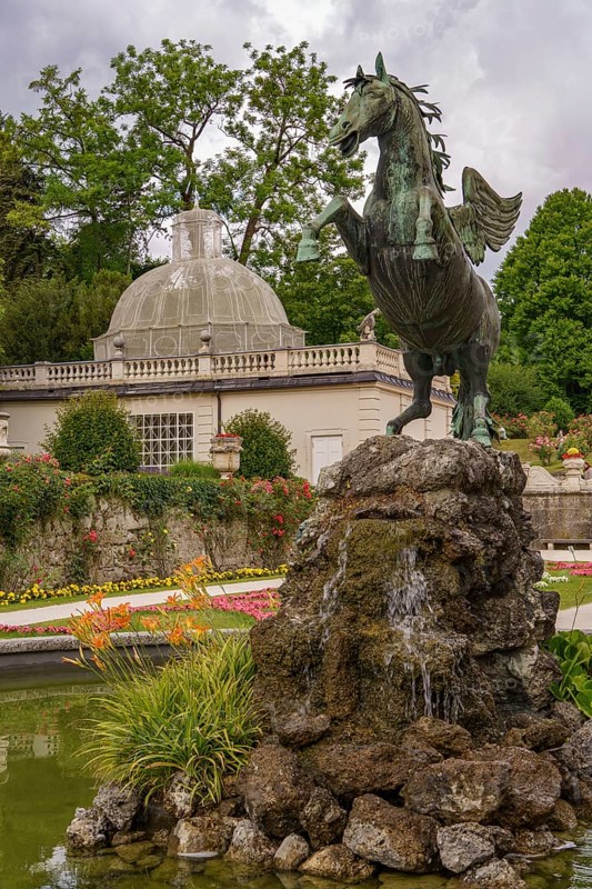 Statue of a rising horse in front of a fountain and historical buildings in the garden, Salzburg, Austria, Europe