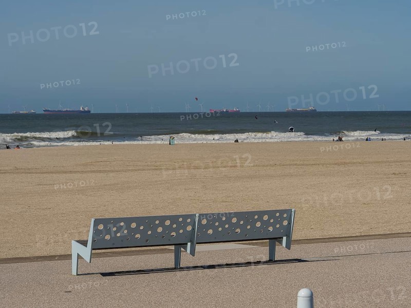 Bench with holes on the beach, in the background the sea and a slightly cloudy sky, scheveningen, the netherlands