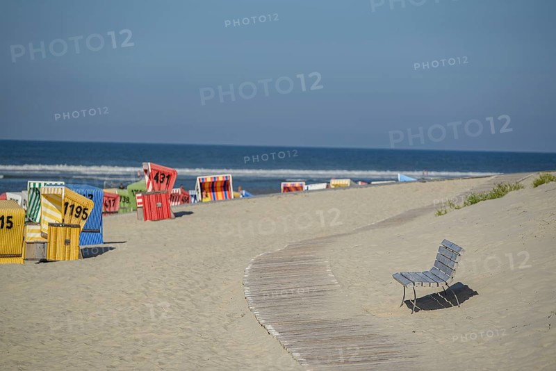 Colourful beach chairs on a sandy beach with a wooden path, quiet atmosphere, langeoog, germany