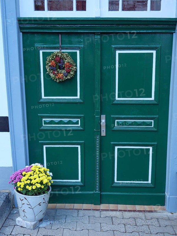 Green double door of a half-timbered house with plant decoration and wreath, Tecklenburg, Germany, Europe