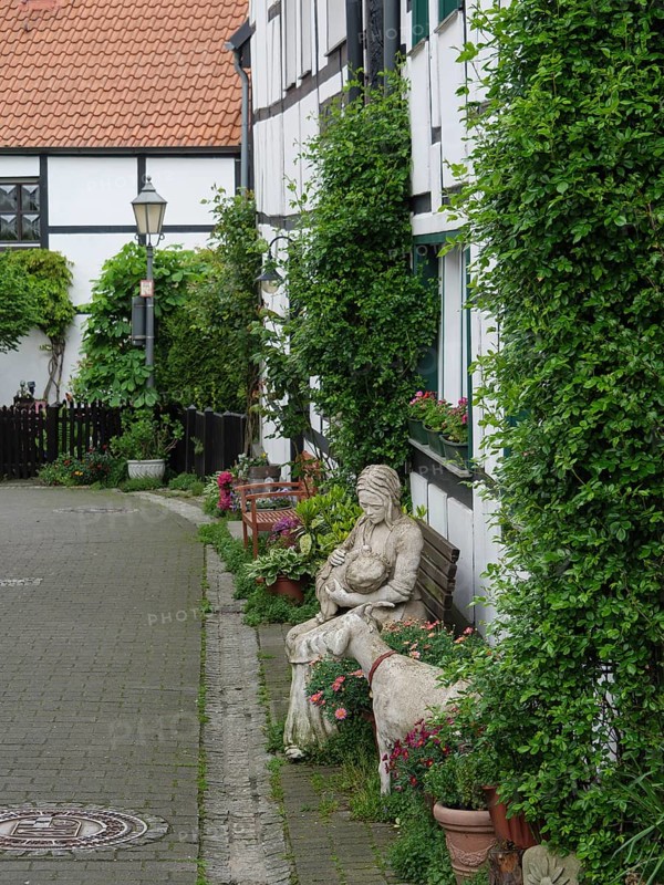 Historic street with half-timbered houses, planted areas and a statue that exudes a peaceful, charming atmosphere, Westerholt, Herten Ruhr Area, North Rhine-Westphalia, Germany, Europe