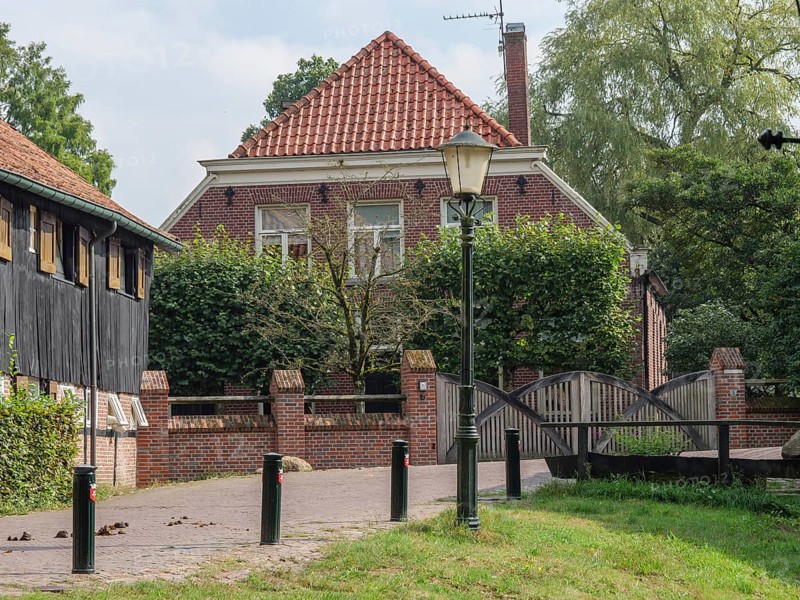 A cosy brick house with an old street lamp and a small bridge in a green garden, haaksbergen, . netherlands