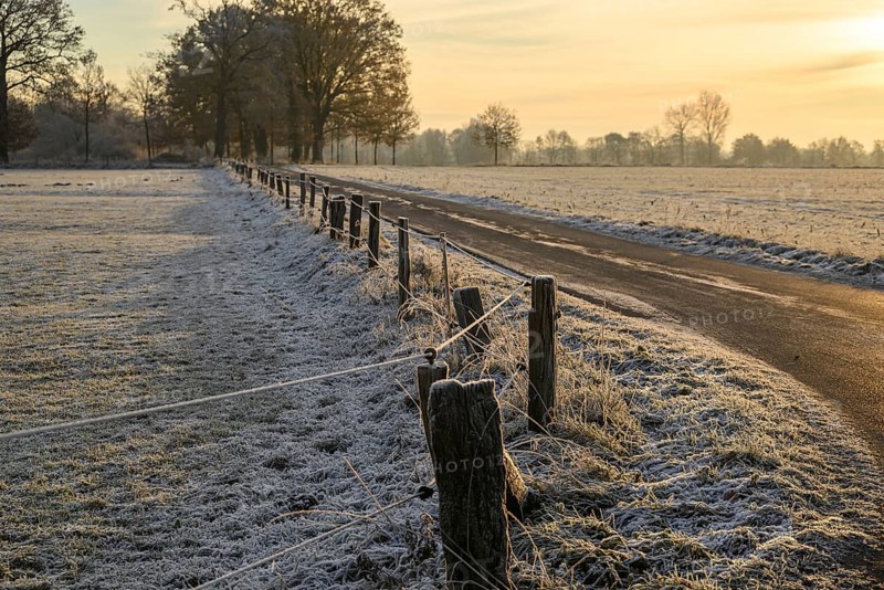 A snow-covered path, lined by a fence, stretches through a winter landscape at sunset, Velen, North Rhine-Westphalia, GERMANY