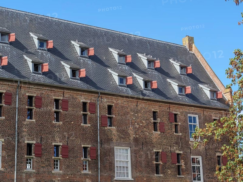 Historic building with many sloping skylights and red shutters under a clear sky, Doesburg, Netherlands
