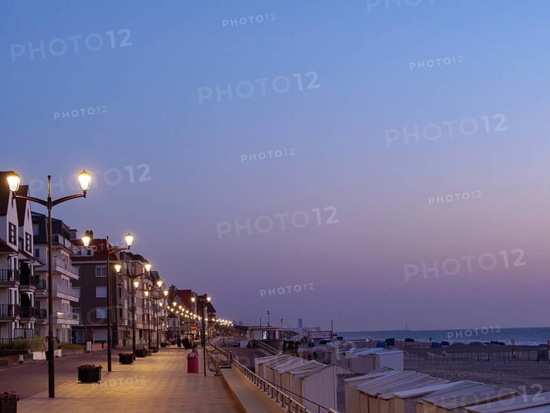 An illuminated promenade with lanterns and buildings at dusk on the beach, de haan, Belgium, Europe