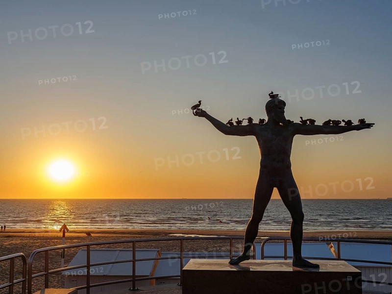A sculpture on the beach at sunset, the sea in the background. The atmosphere is calm and beautiful, DE Haan, Belgium, Europe
