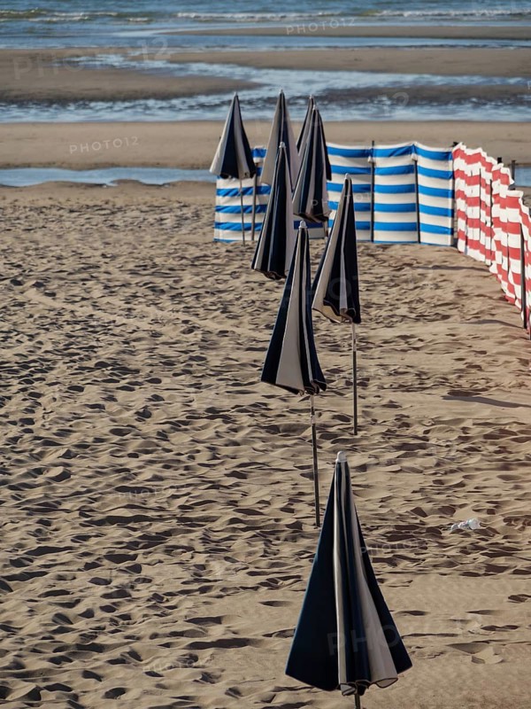 Beach with closed parasols and striped windbreaks by the sea, de haan, Belgium, Europe