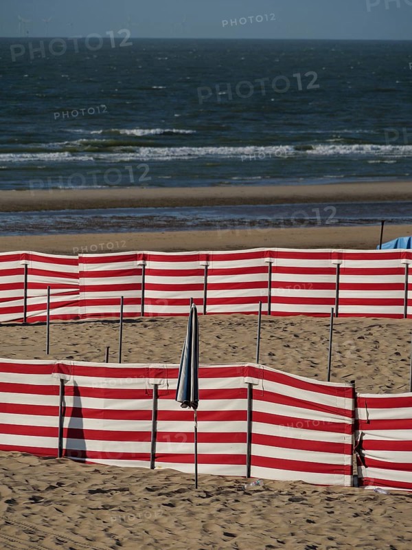 Beach landscape with red and white windbreaks and gentle waves in the background, de haan, Belgium, Europe