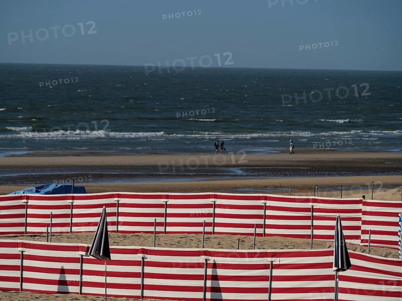 Beach with red and white barriers and a view of the sea and waves on the horizon, de haan, Belgium, Europe