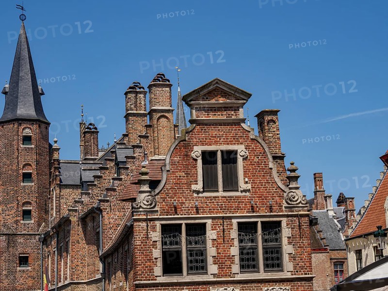 Detailed facades of historic buildings with many bricks and towers under a bright blue sky, Bruges, Belgium, Europe