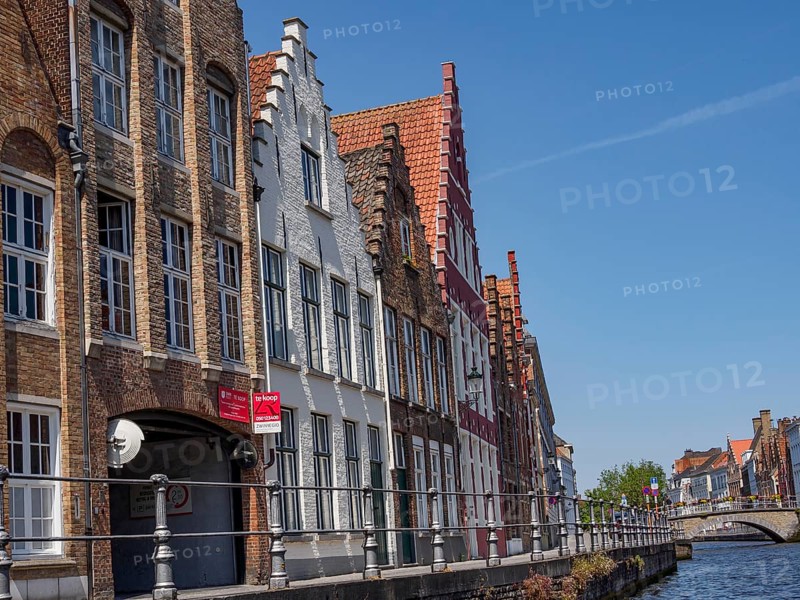 Historic buildings with red roofs and facades on the canal under a blue sky, Bruges, Belgium, Europe