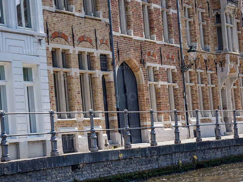 Detailed historic brick faÃ§ade with large windows and a wrought-iron railing on the canal, Bruges, Belgium, Europe