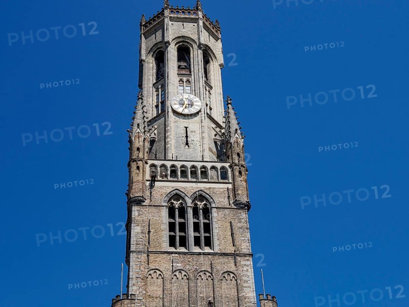 Gothic bell tower with clock in front of a slow sky, Bruges, Belgium, Europe