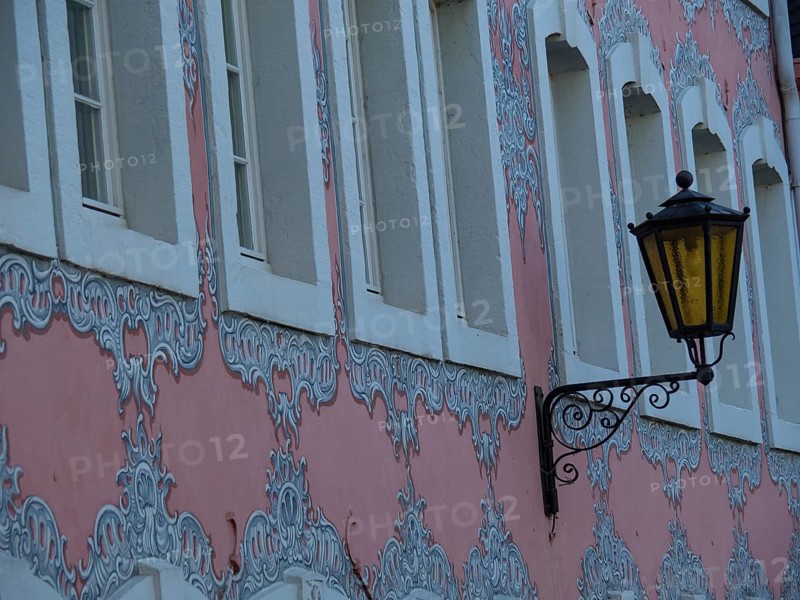 Pink baroque house facade with ornate windows and an old street lamp, trier, germany