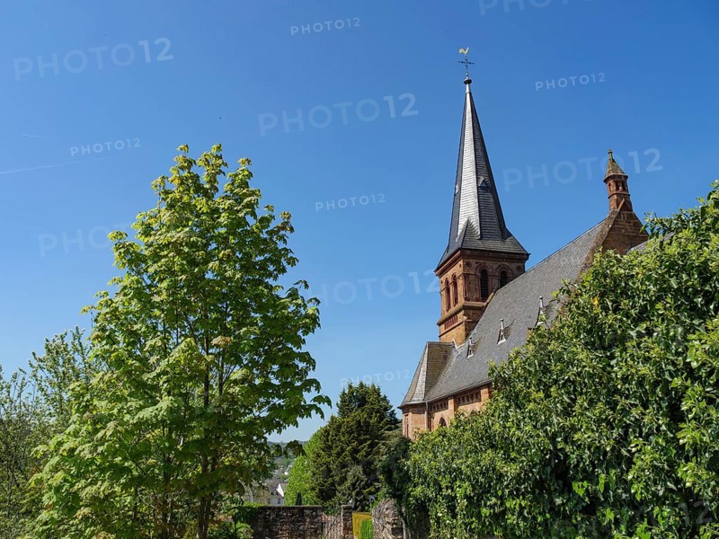 Church tower in a green, summery setting under a bright blue sky, Saarburg, Germany, Europe