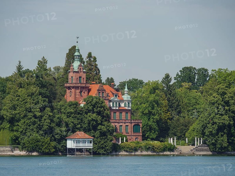 A castle with towers and red bricks, surrounded by trees on the lakeshore, Lindau, Lake Constance, Germany, Europe