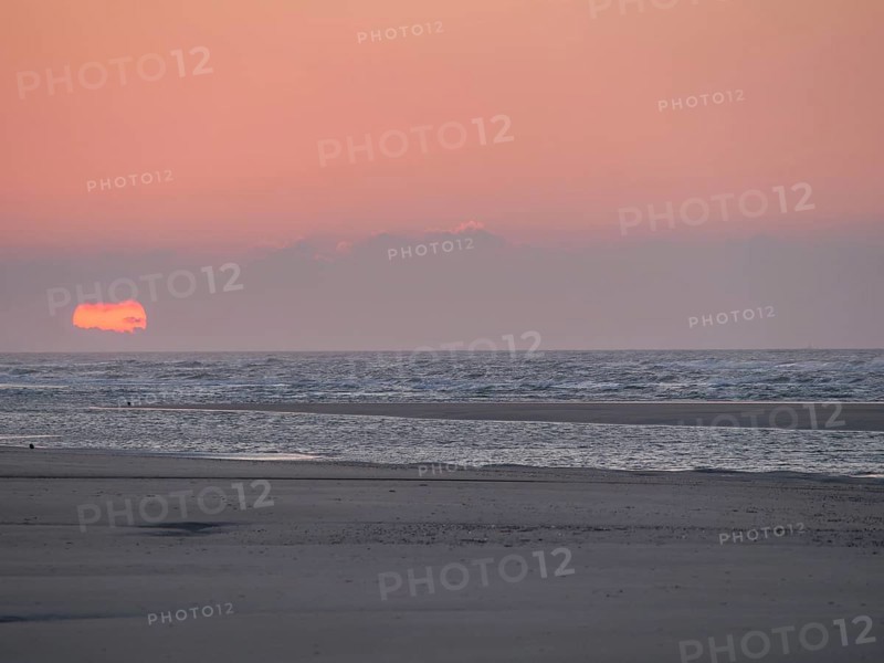 The sun disappears behind the sea on the horizon and colours the sky orange, juist, east frisia, Germany, Europe