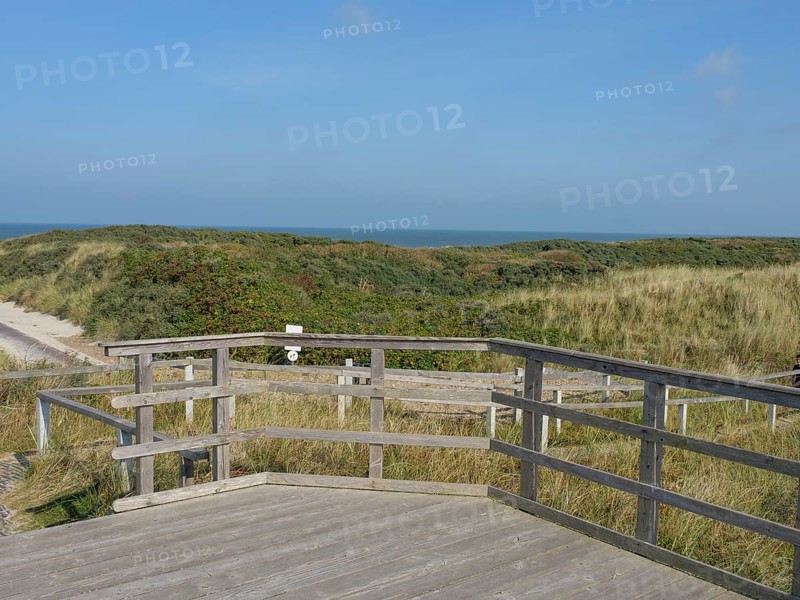 A wooden terrace overlooks the grassy dunes and the calm sea, a peaceful atmosphere dominates the scenery, juist, ostfriesland, Germany, Europe