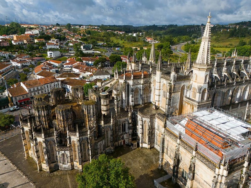 Gothic cathedral with detailed façade in the middle of an urban landscape with houses and green hills, aerial view, monastery, Mosteiro de Santa Maria da Vitoria, 'unfinished chapels', UNESCO World Heritage Site, Batalha, Leiria, Estremadura, Portugal, Europe