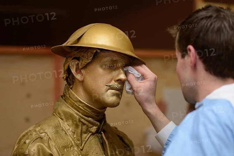 A make-up artist applies gold paint to an actor's face before a performance