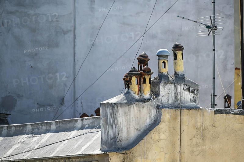Small Mediterranean chimney pots with different caps looking like a miniature village on the rooftop of a traditional apartment house in the city of Thessaloniki, Greece, copy space, selected focus, Europe