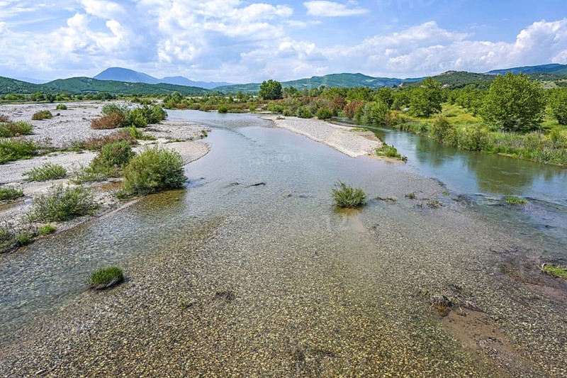 Low water in the riverbed of the Pinios, one of the longest rivers in Thessalia, Greece, now dried after heat and drought, potential effect of climate warming, wide landscape blue sky, copy space, Europe