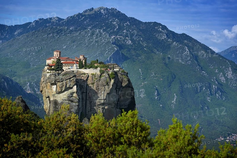Monastery of the Holy Trinity built on the top of a rock in the Meteora complex near Kalambaka, famous tourism attraction in Greece, mountain landscape in the background, blue sky, copy space