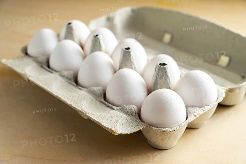 Ten fresh white eggs in a cardboard box on a wooden table, food and Easter concept, selected focus, narrow depth of field