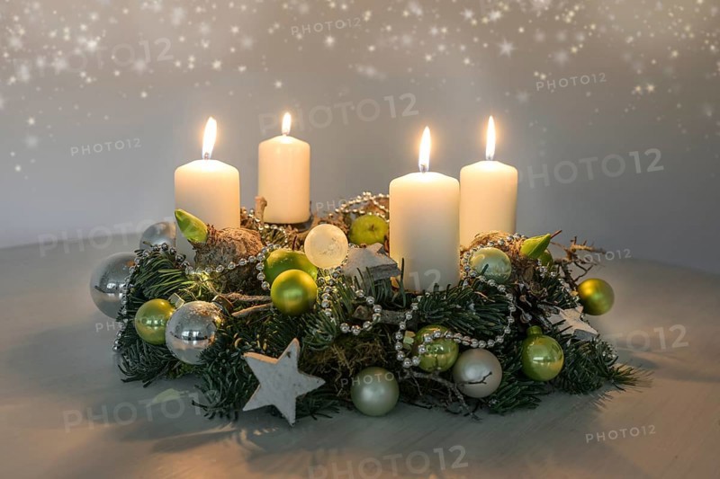 Fourth Advent, wreath with four burning white candles and green Christmas decoration on a table, home decor for the fourth Sunday, copy space, selected focus, narrow depth of field