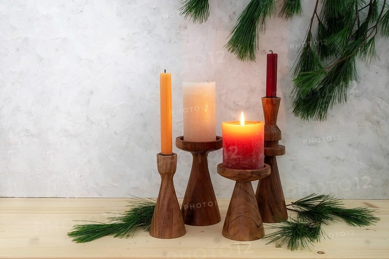 Four candles on wooden stands, one is lit for the first Advent, pine branch decoration, light wooden board and rustic plaster background, copy space, selected focus, narrow depth of field