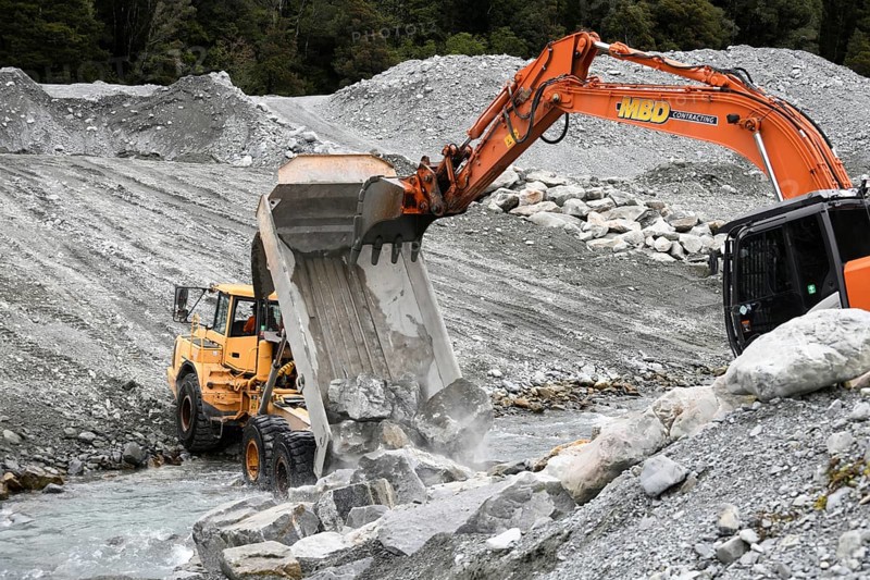 OTIRA, NEW ZEALAND, SEPTEMBER 19, 2019: A tip truck dumps a load of rock to create flood water control on a West Coast river just above a railway bridge