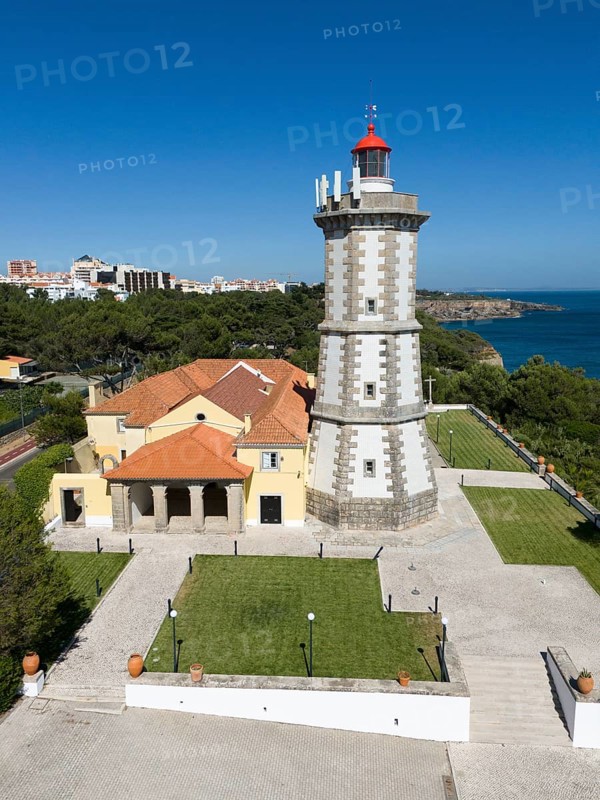A lighthouse with a red top next to a yellow building, surrounded by a tarmac path and a view of the sea, aerial view, Farol da Guia, Cabo da Guia, Cascais, Lisbon, Lisboa, Portugal, Europe