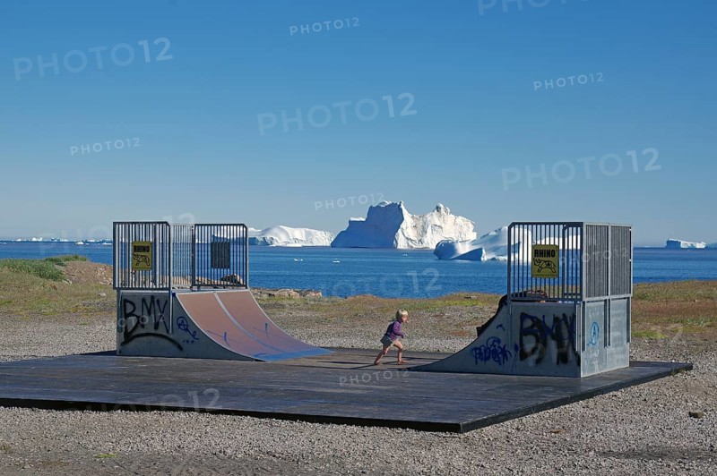 Halfpipe near a beach with icebergs in the sea and a BMX-riding kid, blue sky, end of the world, Disko Island, Disko Bay, Greenland, Denmark, North America