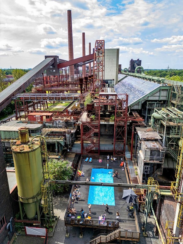 The works swimming pool at the Zollverein coking plant, always in operation during the North Rhine-Westphalia summer holidays, former art object, now bathing fun against the backdrop of what was once Europe's largest central coking plant, closed in 1993, part of the UNESC World Heritage Zollverein Coal Mine Industrial Complex, Essen, North Rhine-Westphalia, Germany, Europe