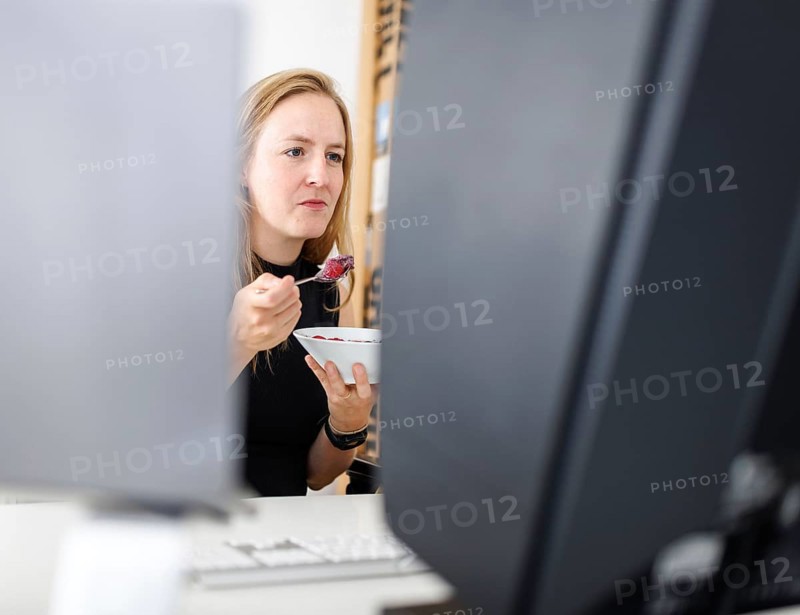 Food at work: A woman eats muesli with fruit in the office. Berlin, 25.07.2024
