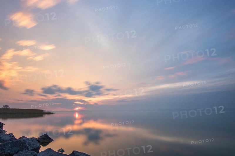 Water landscape, taken from the shore of a calm lake. View over the reflecting water to the horizon at sunset. Siofok harbour, Lake Balaton, Hungary, Europe